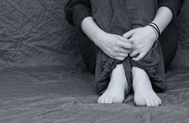 불안에 떨고 있는 여성이 쭈구려 앉은 하체를 촬영한 흑백사진