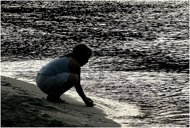 해변가에 여자가 웅크려 앉아 있는 사진